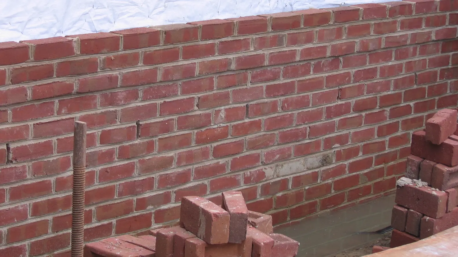 Bricklayer laying a course of bricks in mortar with a trowel