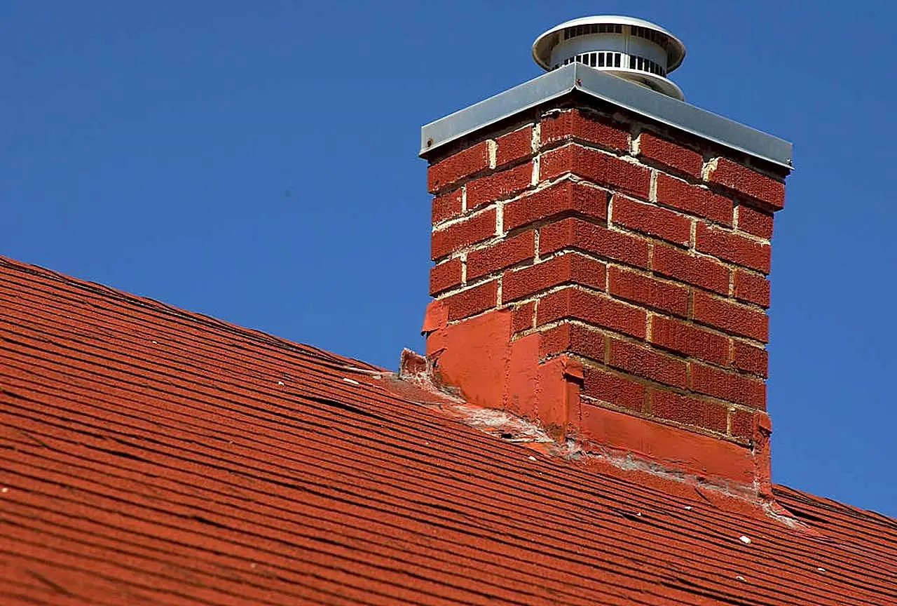Brick chimney rising above a house roof