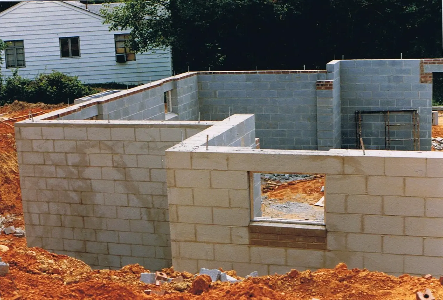 New concrete block (CMU) walls rising from a red-clay building lot