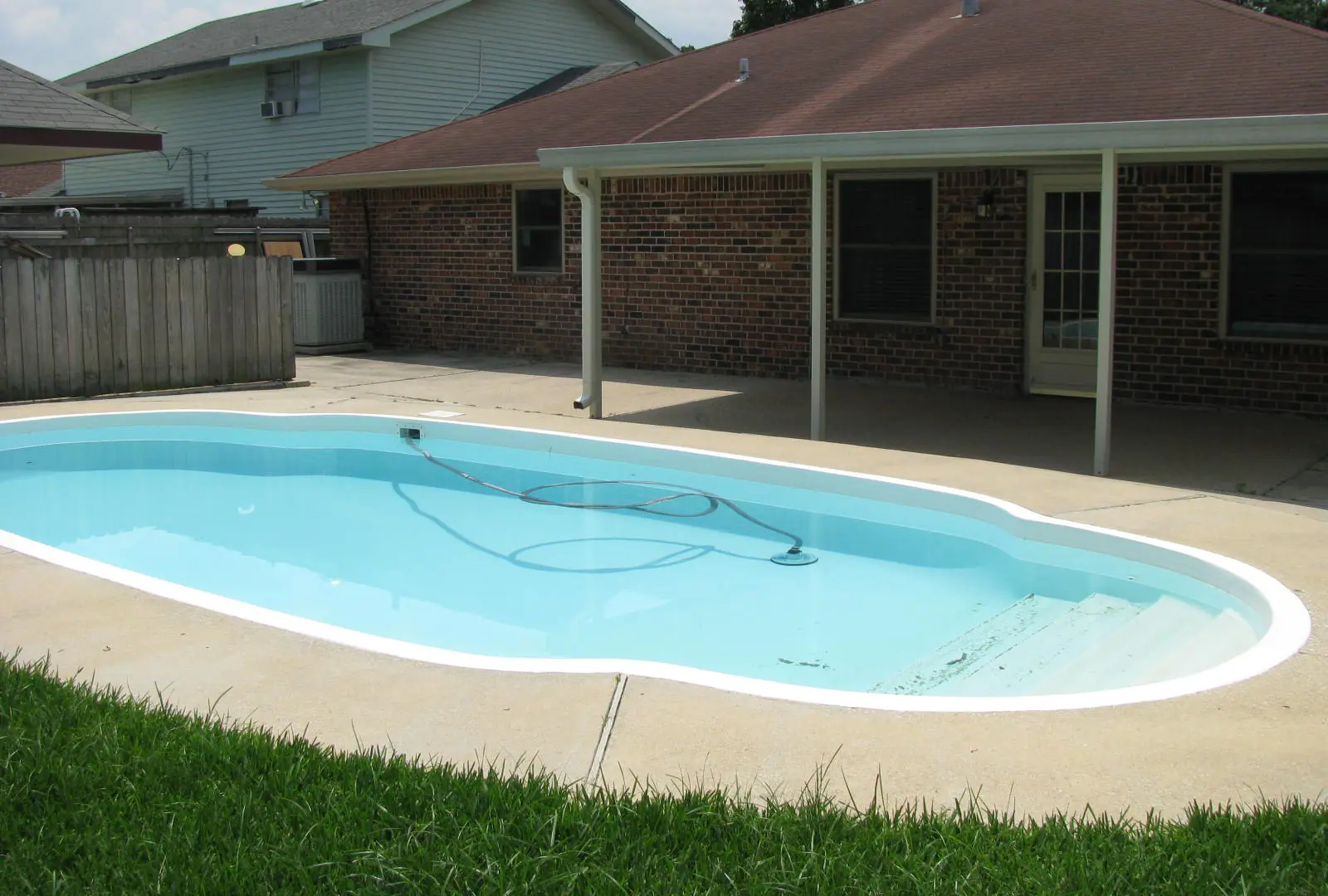 Concrete pool deck around a backyard swimming pool