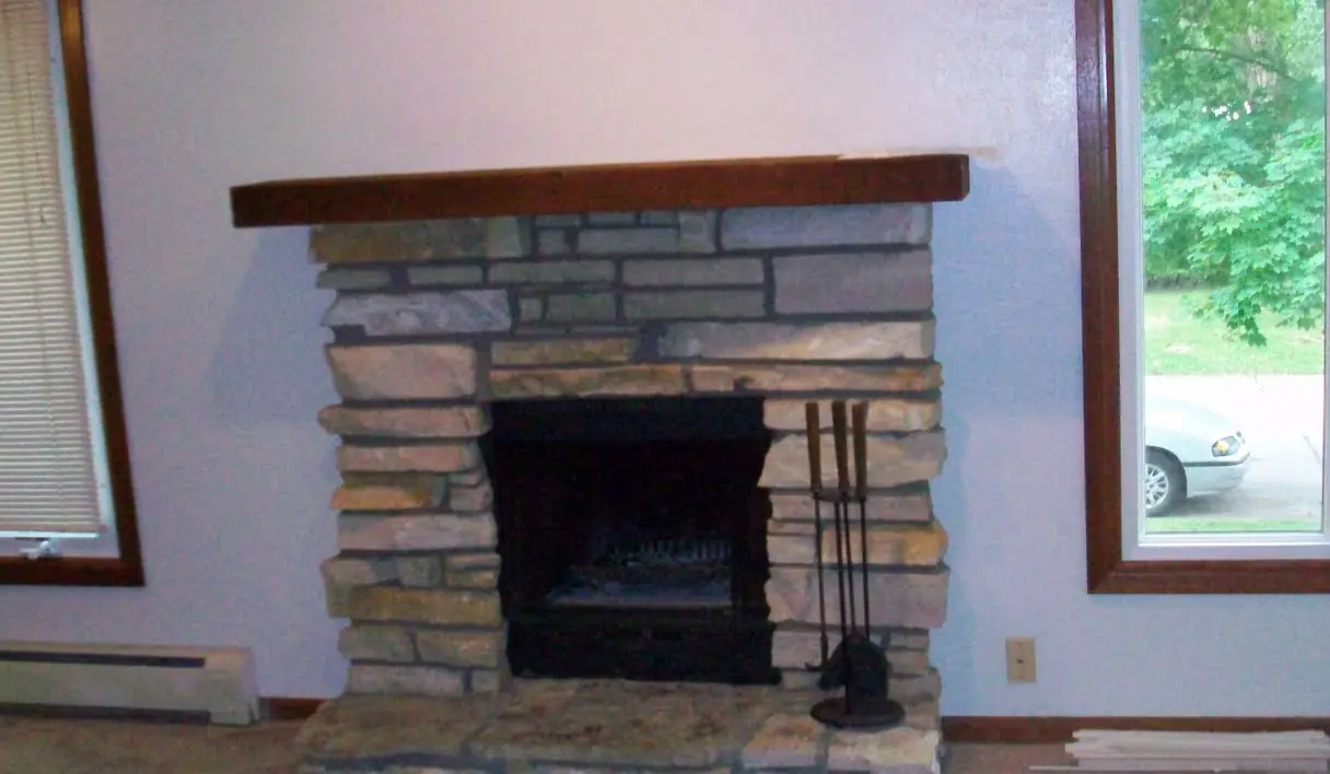 Stacked natural stone fireplace with a wood mantel and stone hearth