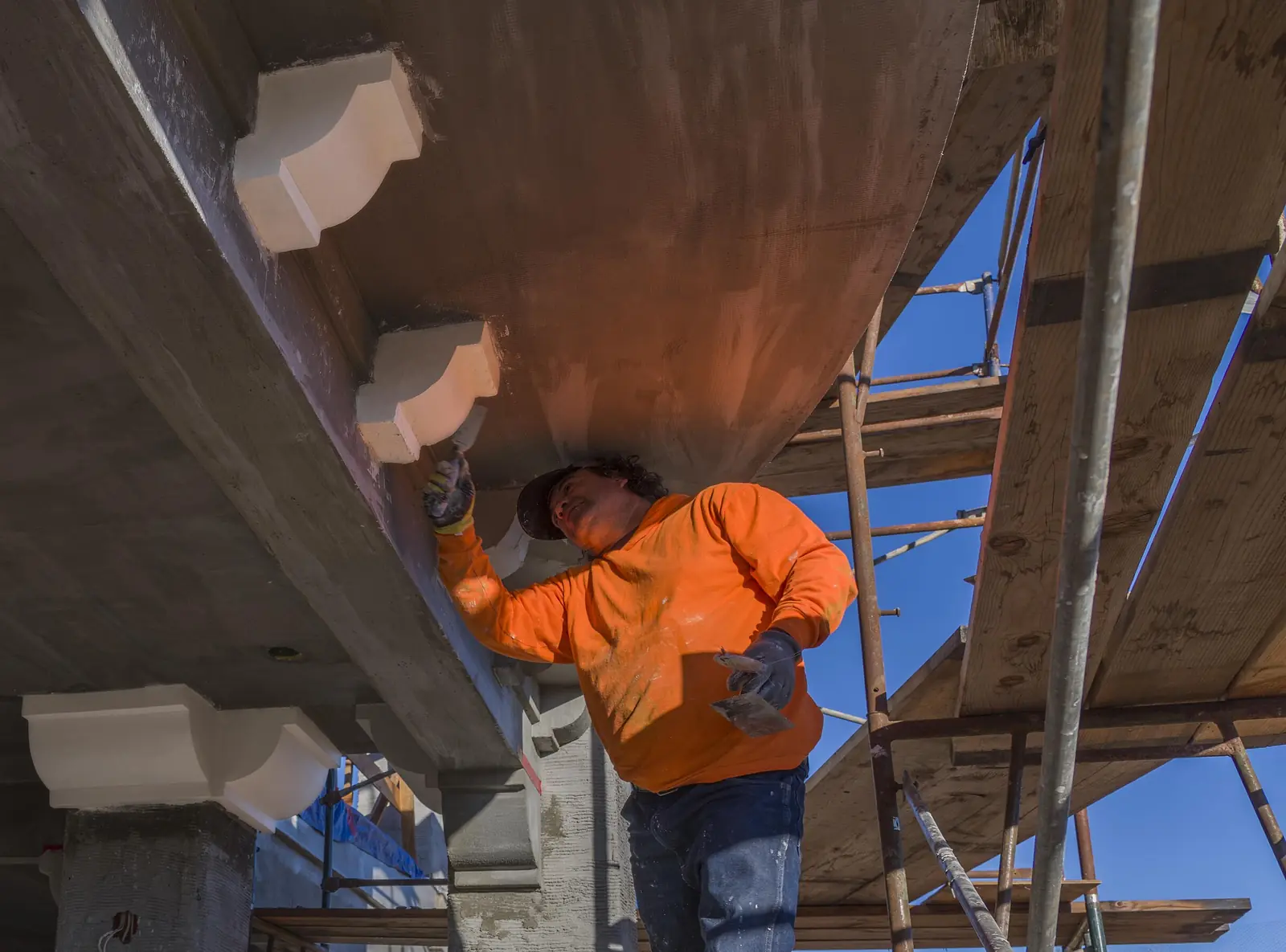 Plasterer on scaffolding applying exterior stucco to a house